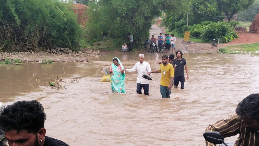 कालीसिंध नदी में उफान के दौरान लोग पानी पार करते हुए