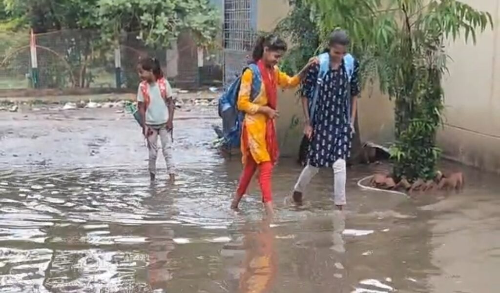 पानी में खड़ी छात्राएं और अभिभावक